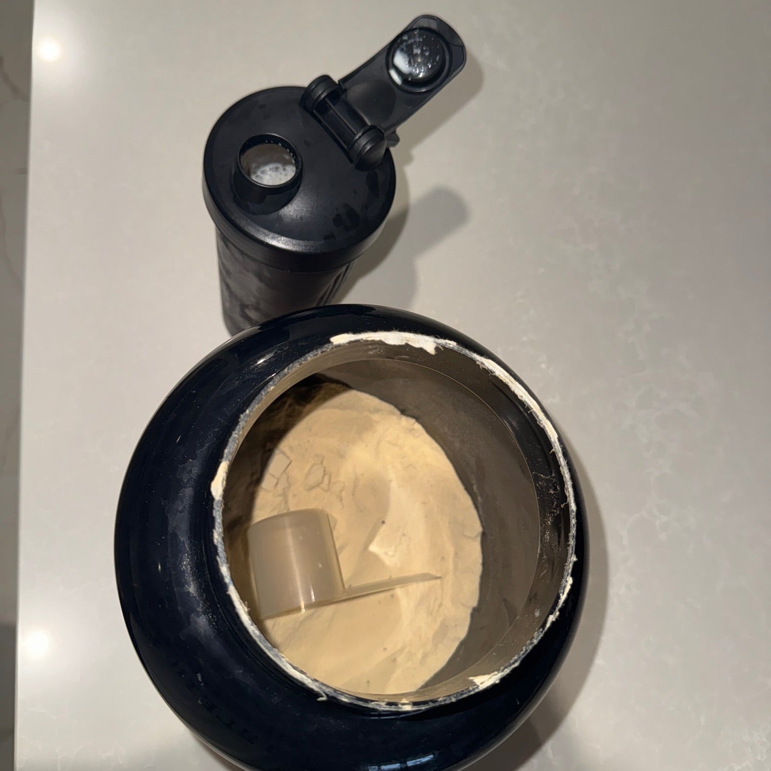 Photo of Protein Shake in a shaker next to Protein powder container.