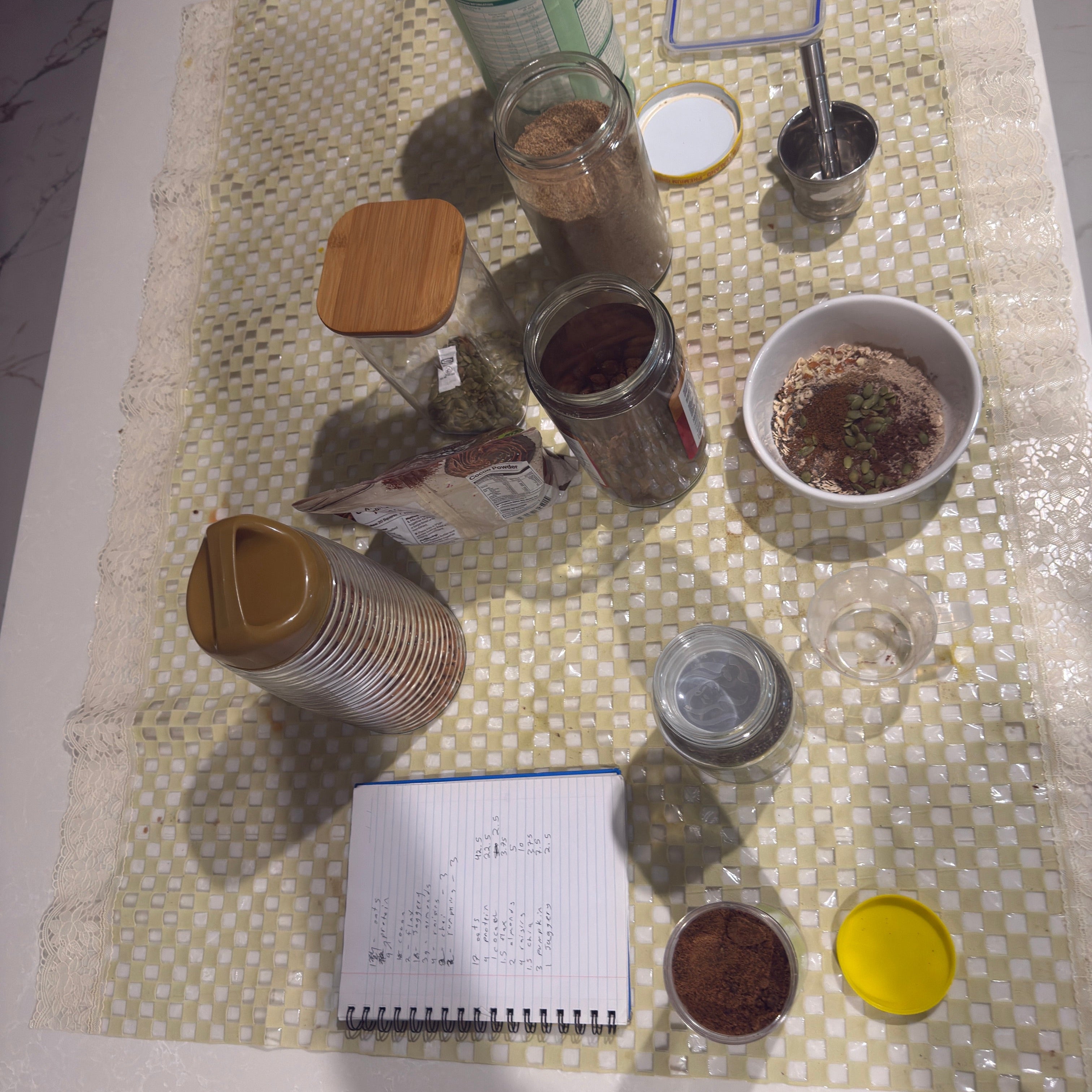 Tabletop setup with various containers, a notebook, and a smartphone on a textured surface.
